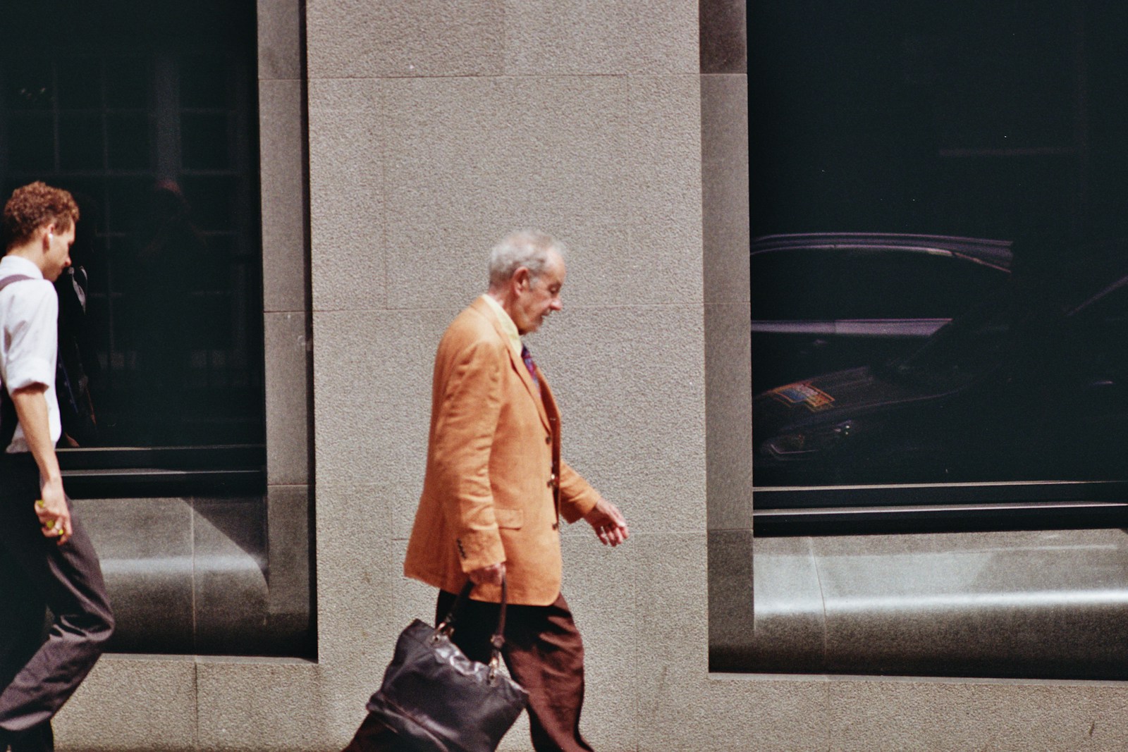 An older man walks down a city street.