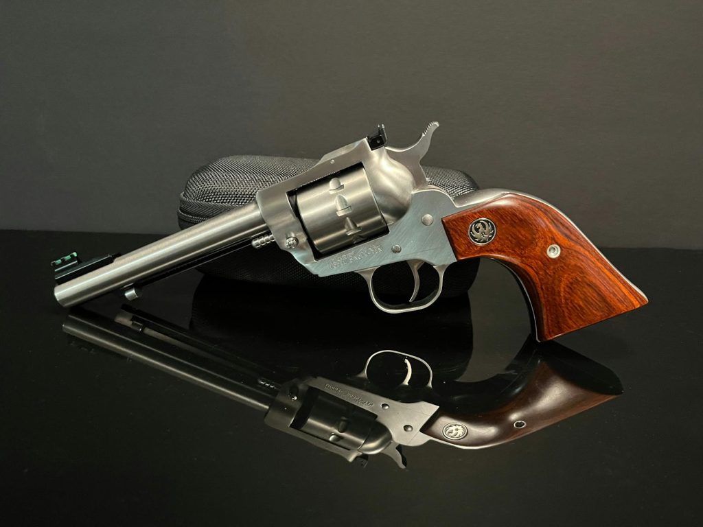 A classic silver revolver displayed on a reflective surface with a gray background, perfect for antique firearm enthusiasts.