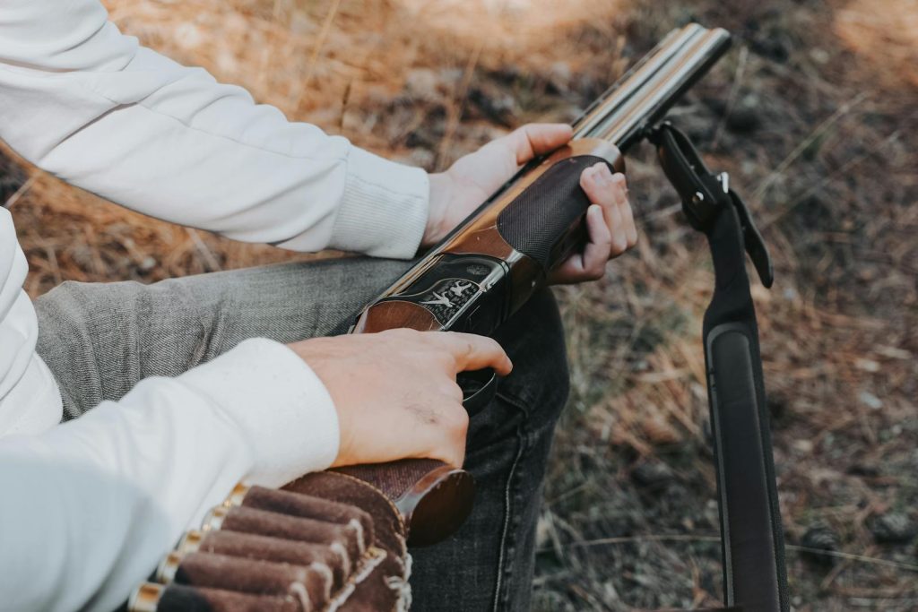 Close-up of a person loading a shotgun outdoors, ready for hunting.
